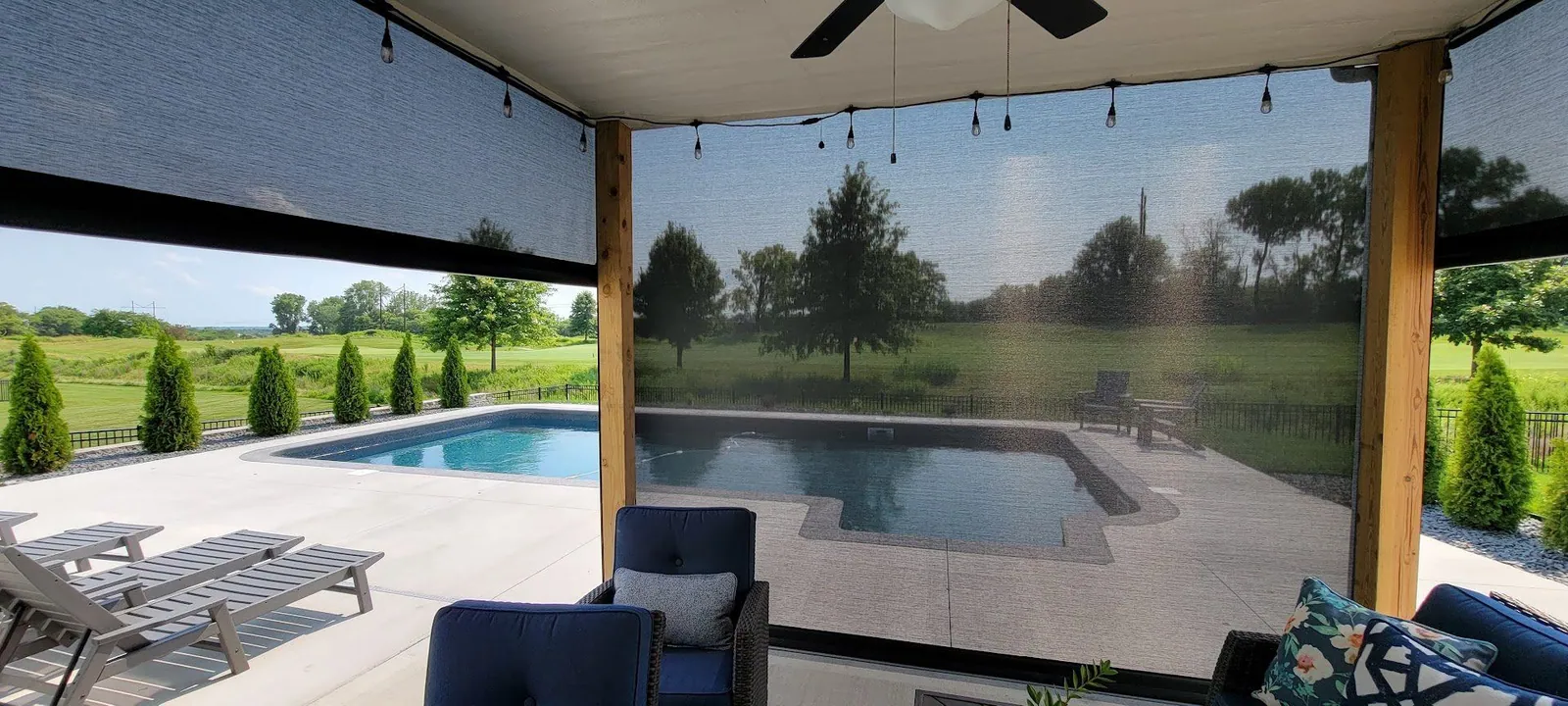 Exterior patio shades lowered around a covered patio beside a pool