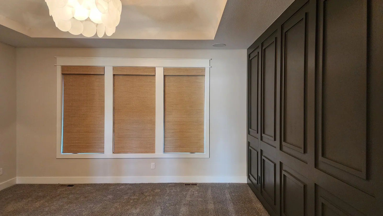 Natural woven shades on three windows in an empty room, installed by Solar Shield Blinds