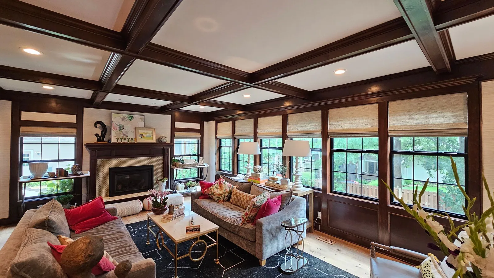 Natural woven shades along a wall of windows in a living room with a coffered ceiling