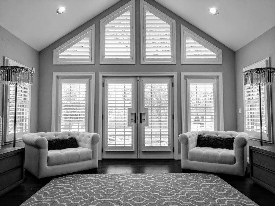 Plantation shutters on angled windows and french doors in a sitting room, installed by Solar Shield Blinds