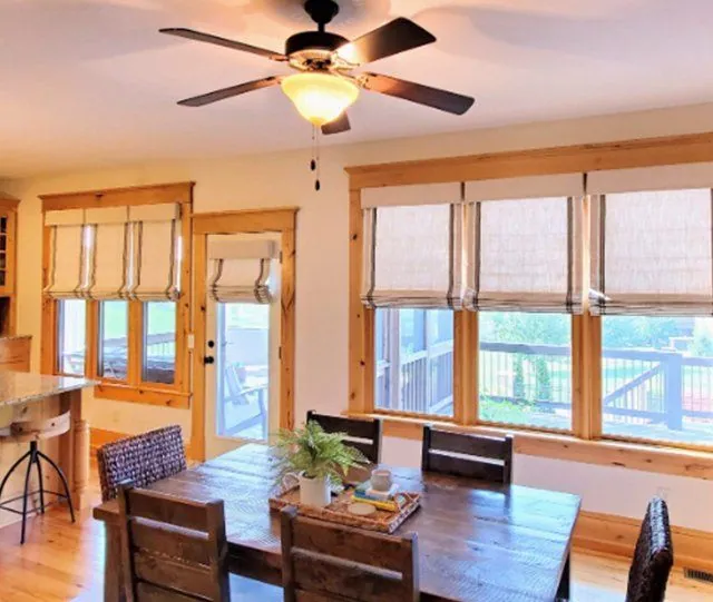 Roman shades on the windows of a dining room with wood trim