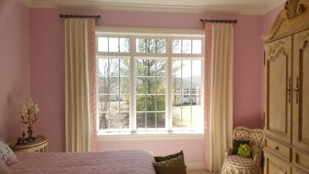 Cream drapery panels framing a bedroom window, installed by Solar Shield Blinds