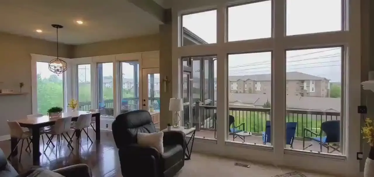 An open living and dining room with tall windows and patio doors out to a deck