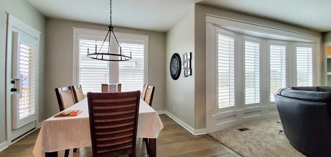 White plantation shutters on dining room windows, installed by Solar Shield Blinds