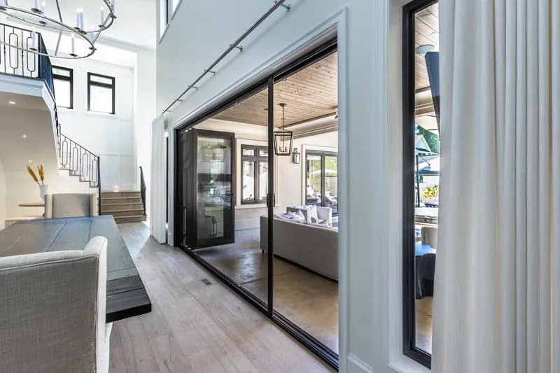 A wall of multi panel sliding glass doors opening a living room onto a covered patio