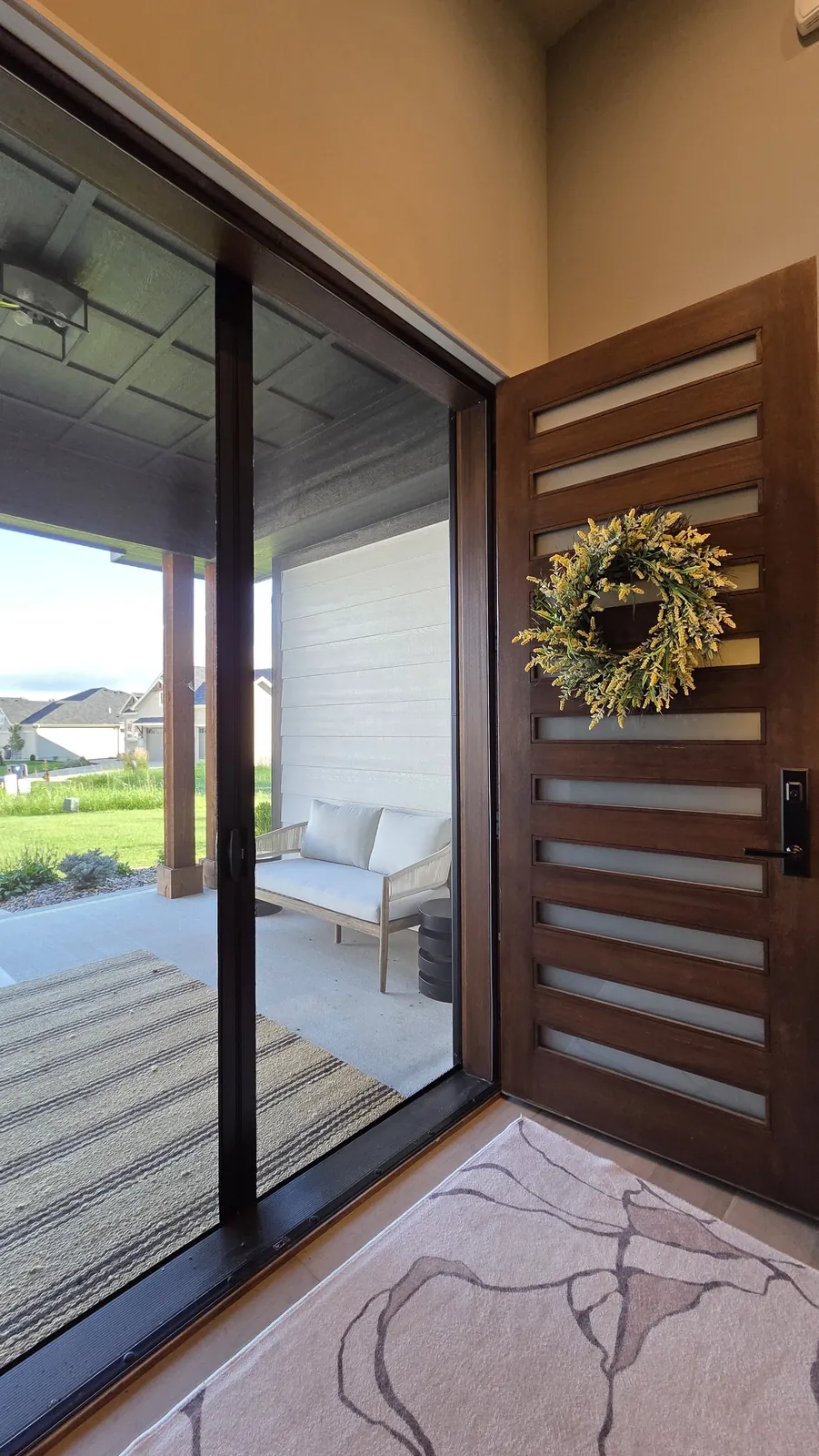 A Sliding Screen closed across an open front doorway, seen from inside beside the open wood door on the right