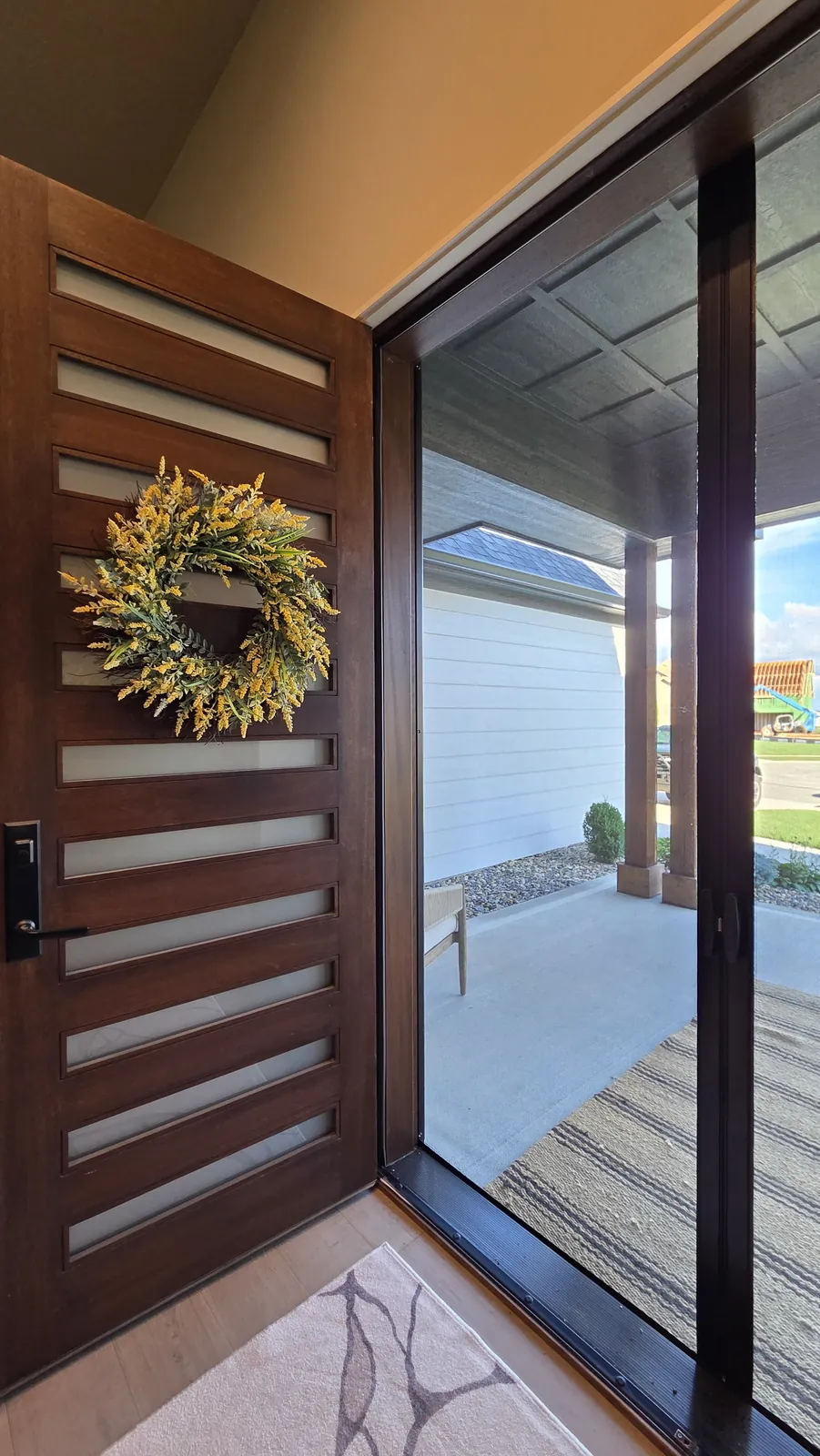 A Sliding Screen closed across an open front doorway, seen from inside beside the open wood door on the left