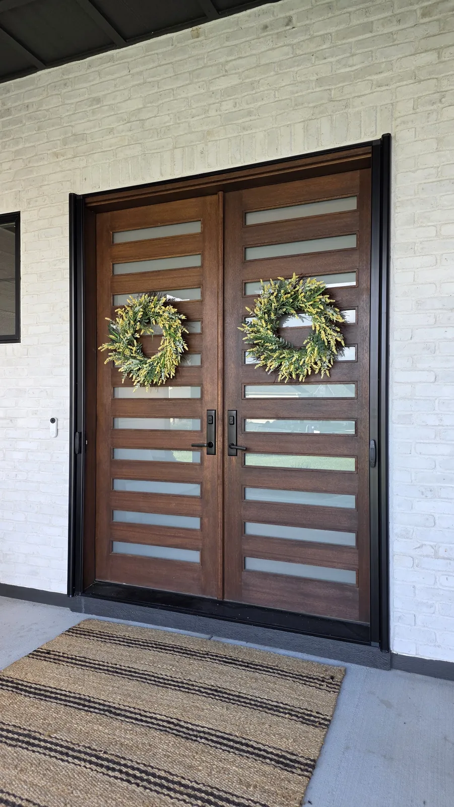 Wood double front doors with wreaths, closed, on a covered front porch