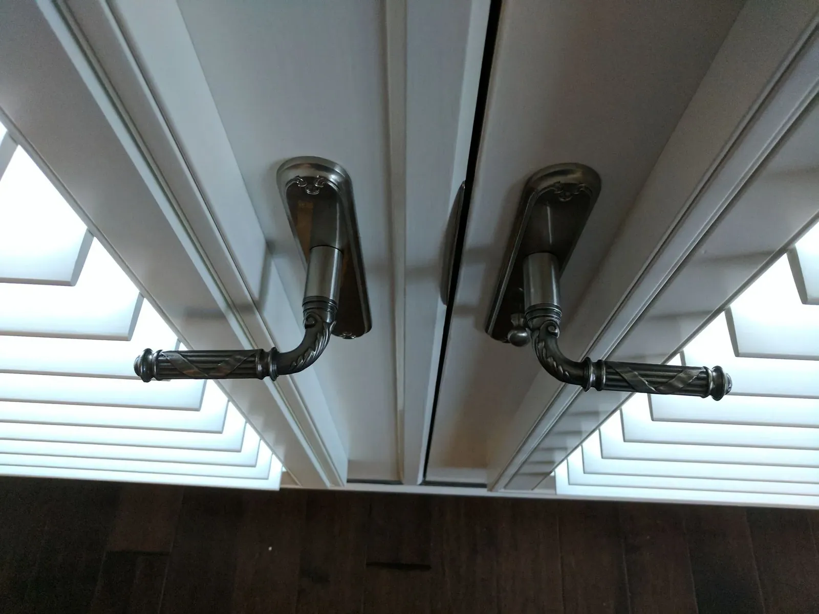 Plantation shutter on a French door with the panel cut around the lever handle