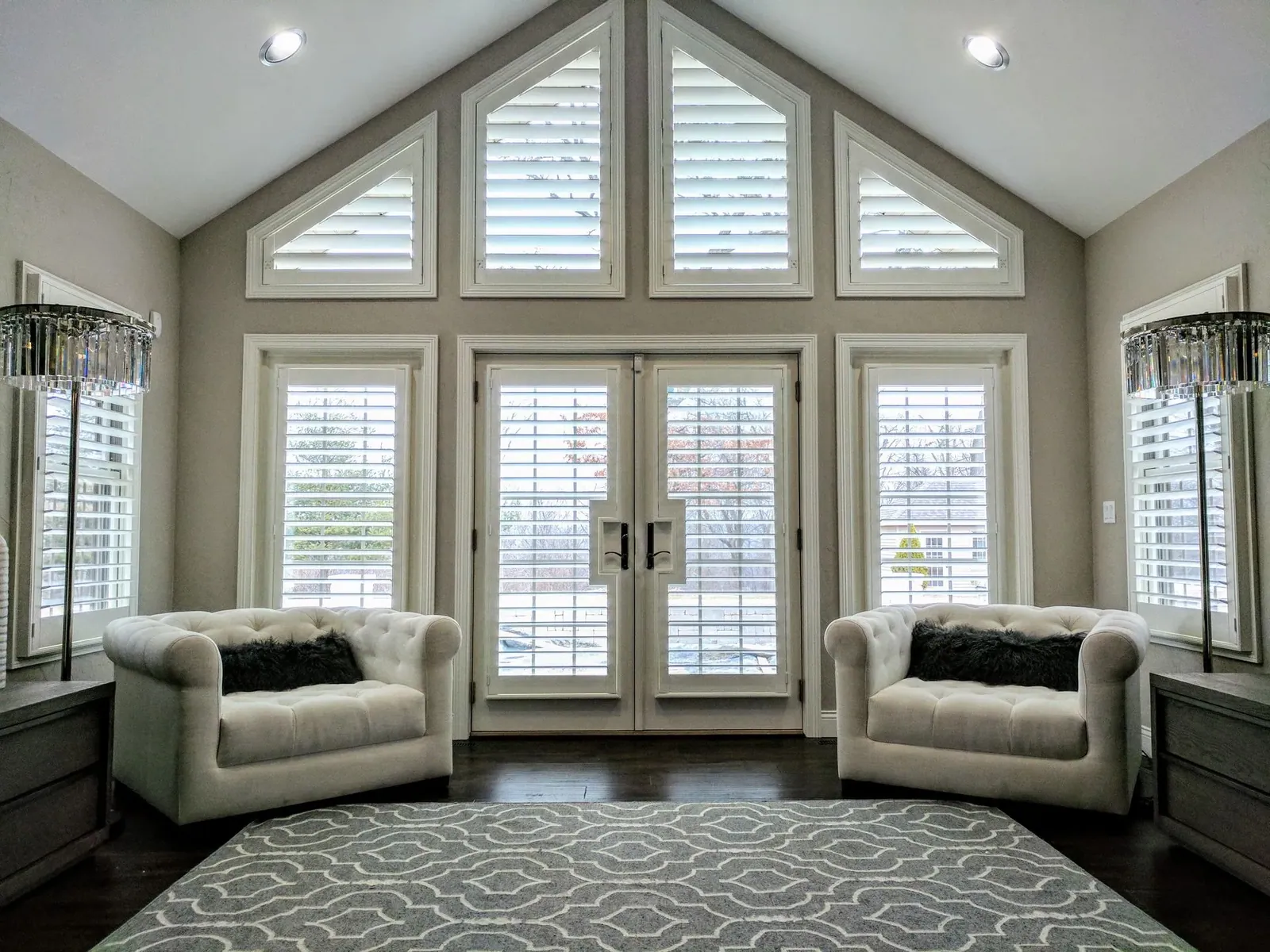 Plantation shutters across a full wall of French doors, side windows and arched transoms