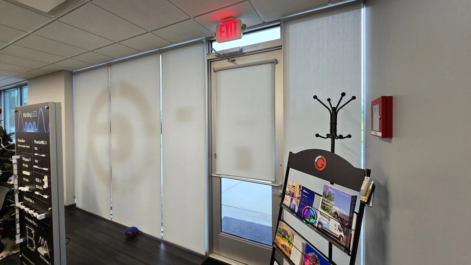Roller shades across an office lobby, with a matching shade on the entry door