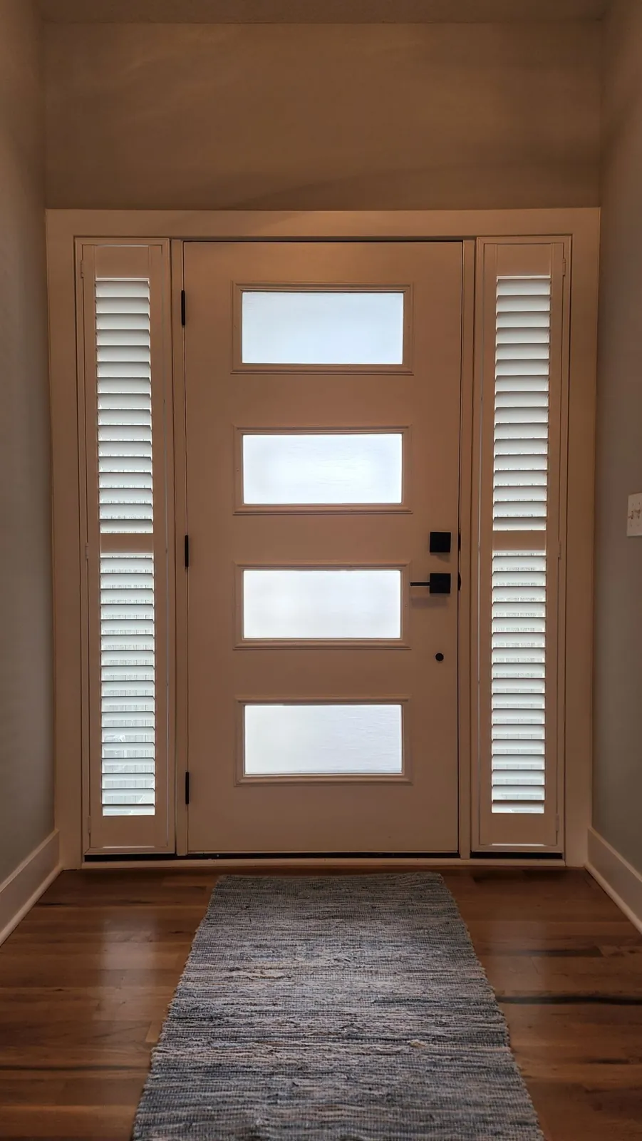 Shutters on the sidelights of a door with four frosted lites