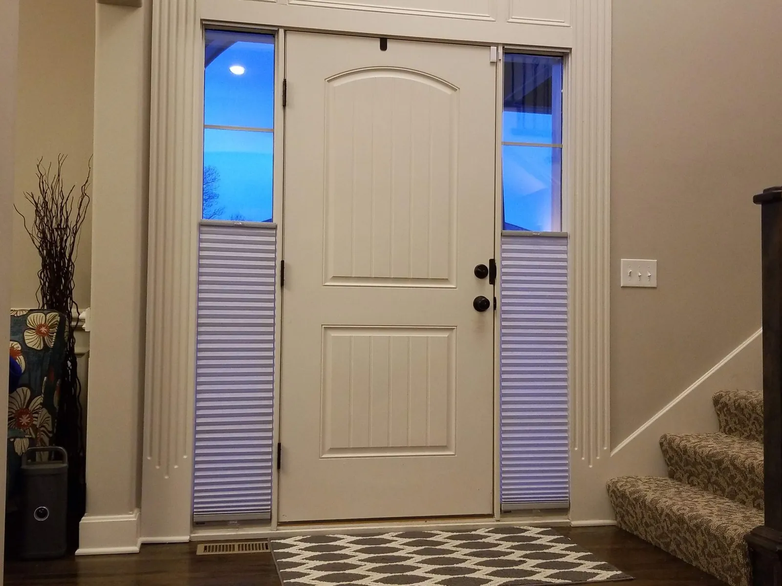 Top down bottom up honeycomb shades on the sidelights of a front door at dusk