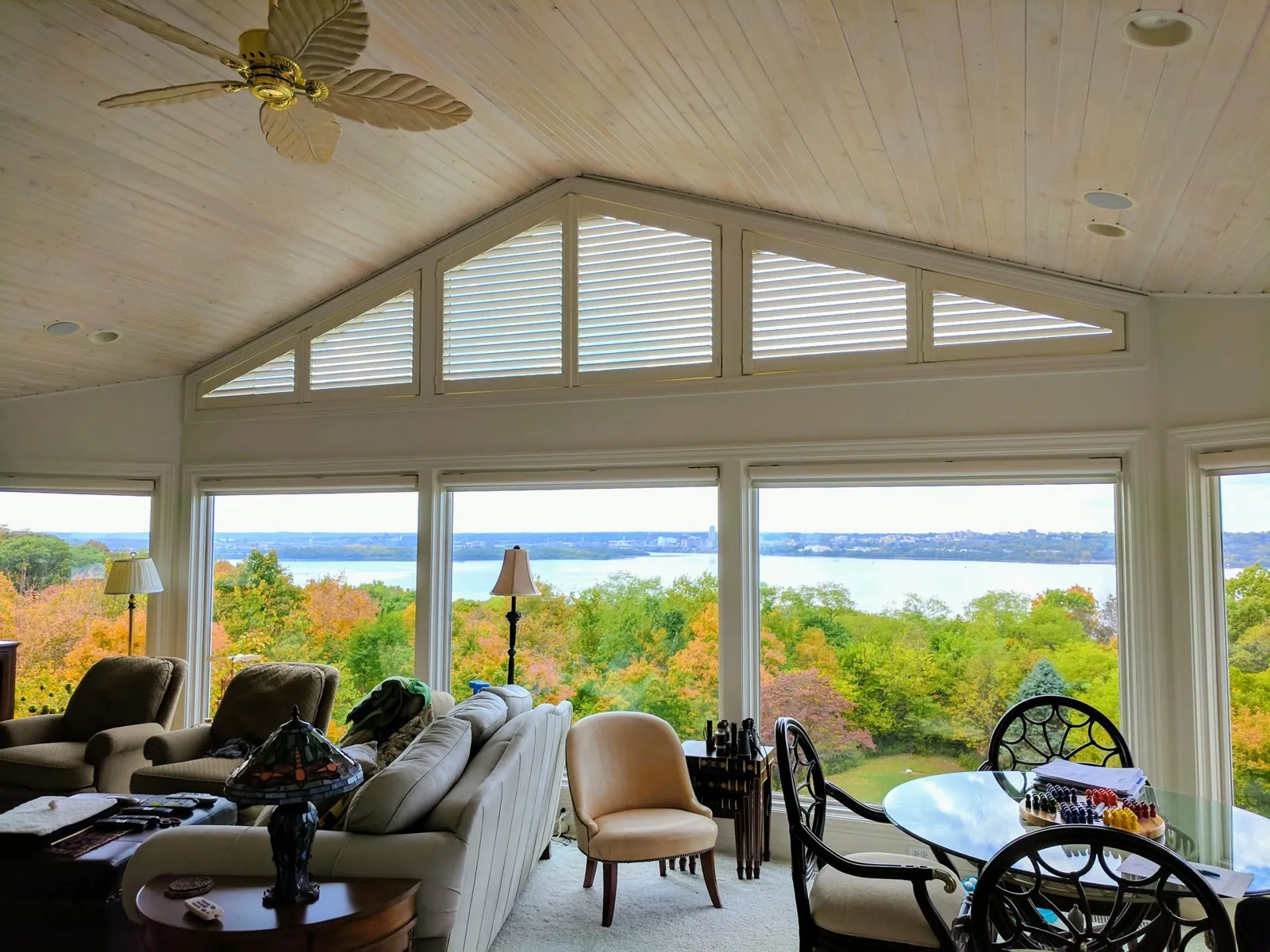 Angle top windows with roller shades in a vaulted sunroom looking out over a lake