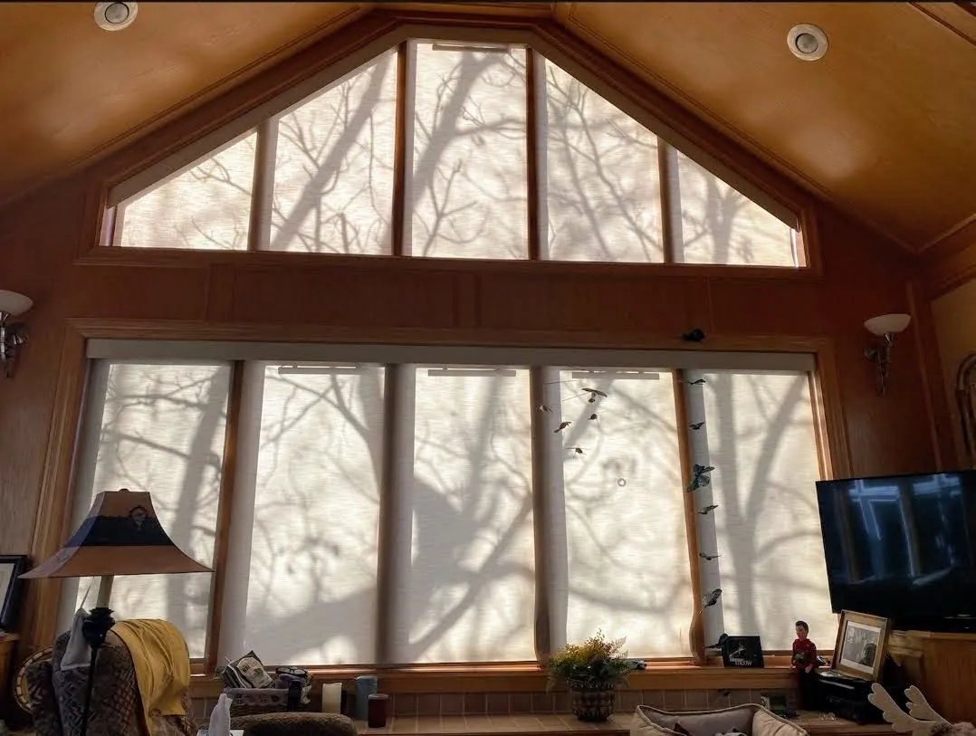 Light filtering roller shades on angle top windows in a vaulted wood paneled great room