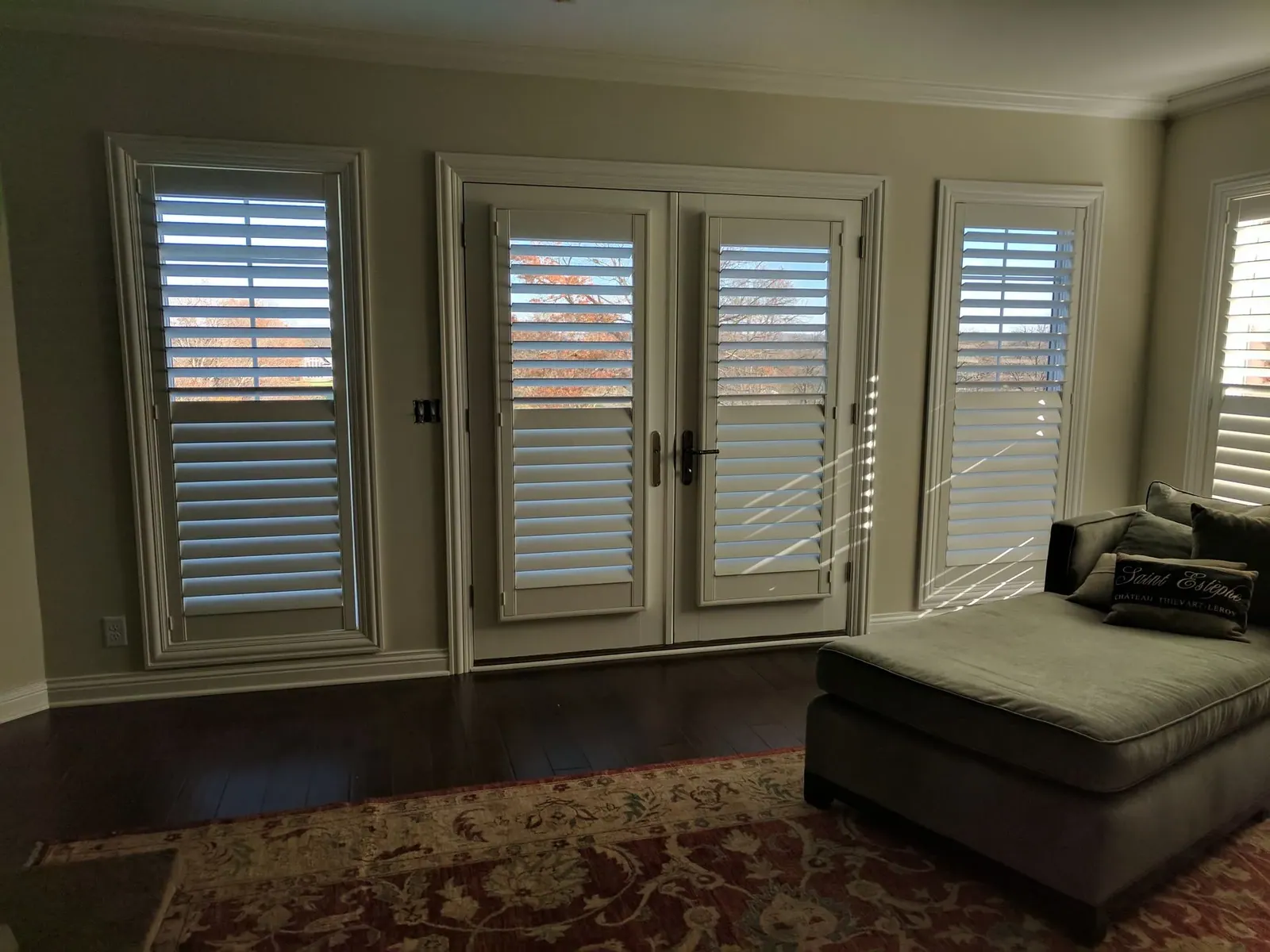 Plantation shutters on French doors and the windows either side, louvers tilted for light