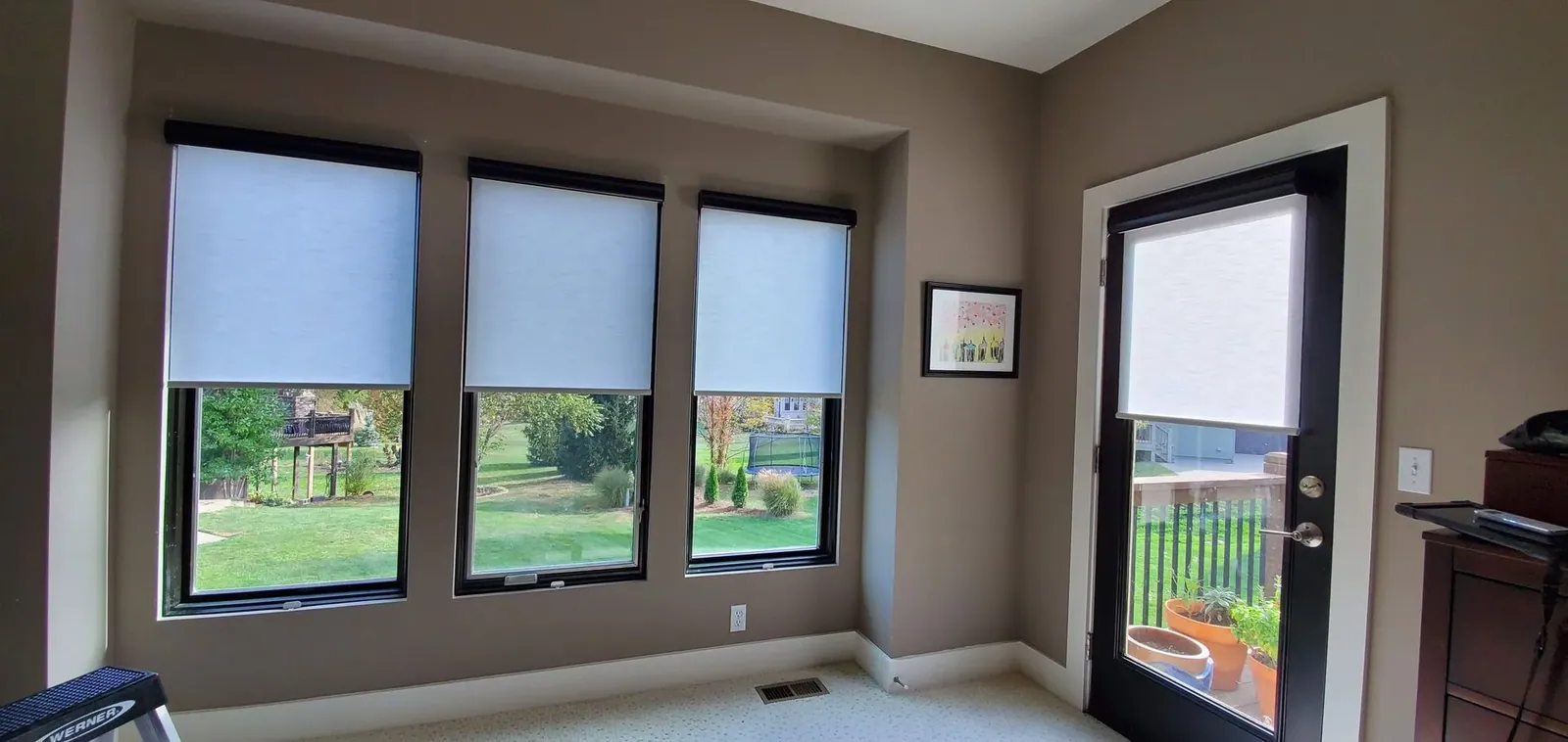 Roller shades on three windows and the swing door beside them