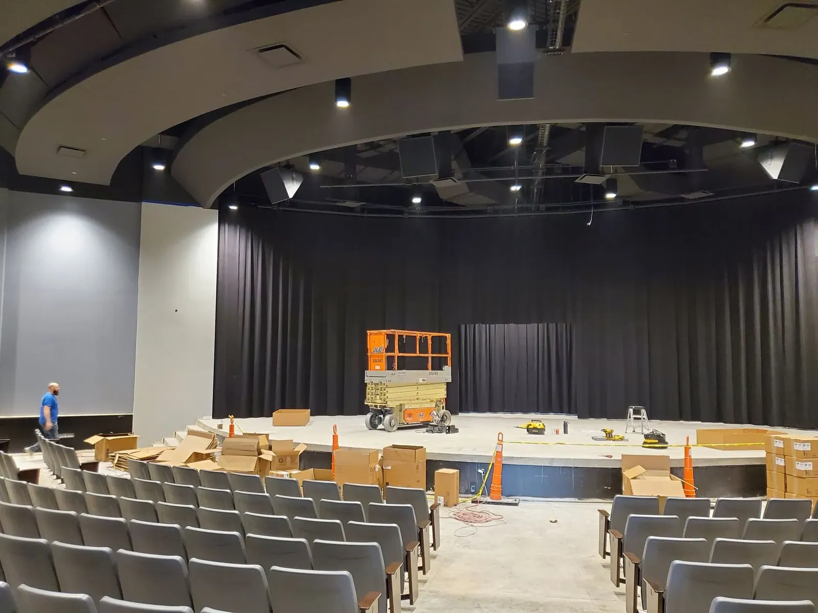 Black stage curtains hung in a new auditorium with a lift still on the stage