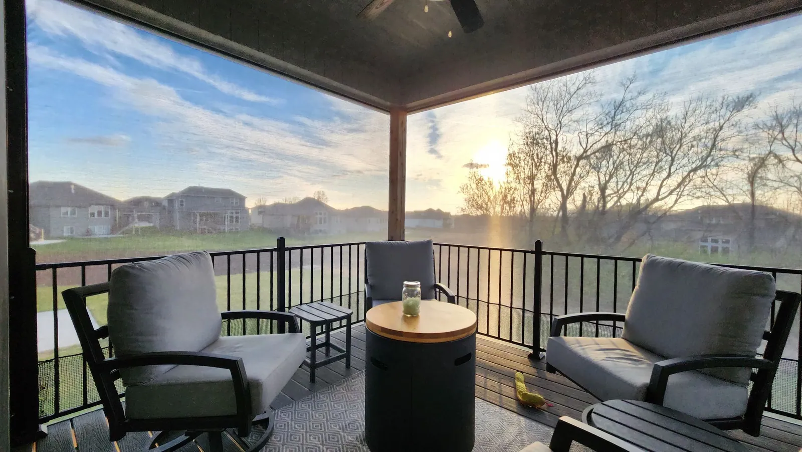Deck chairs behind lowered screens as the sun sets over the neighborhood, installed by Solar Shield Blinds