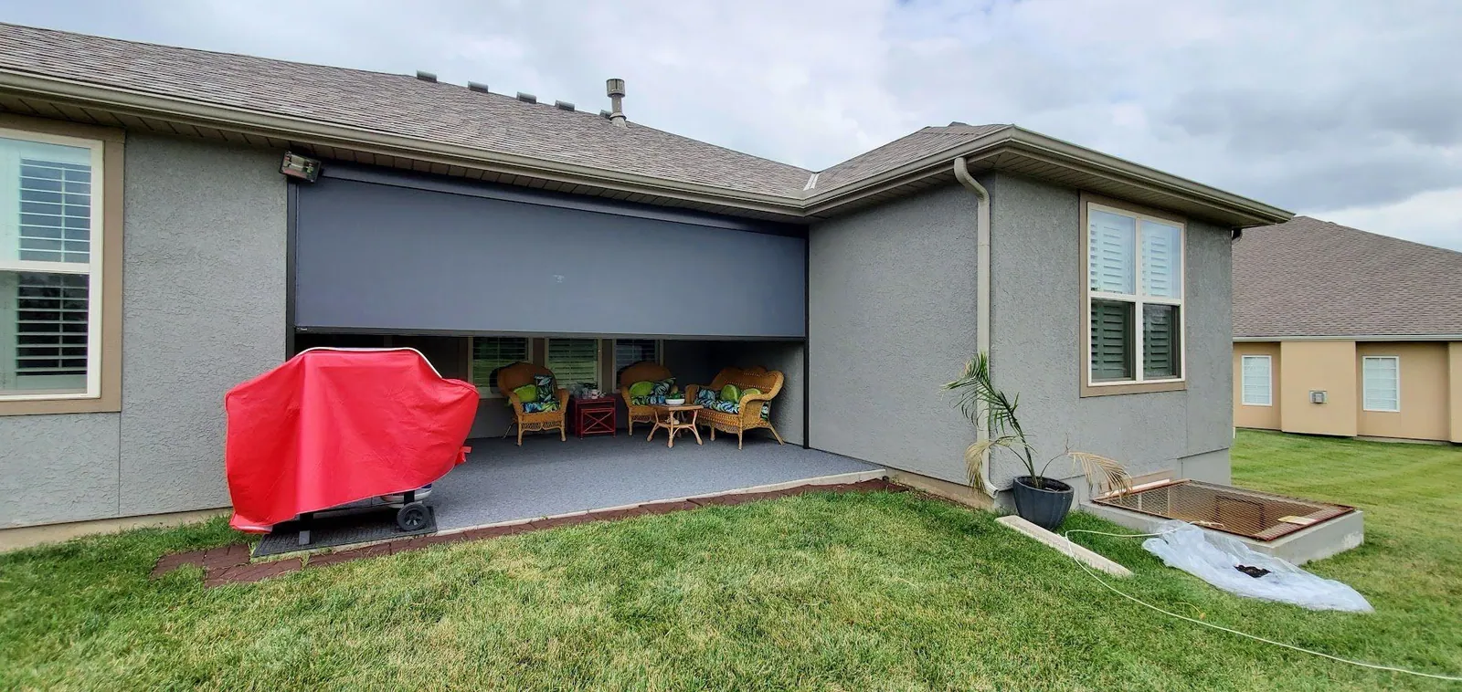 The same ranch patio with the shade half lowered, the chairs showing beneath it, installed by Solar Shield Blinds