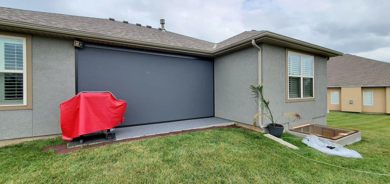Ranch home with the patio shade lowered and a grill under its cover, installed by Solar Shield Blinds