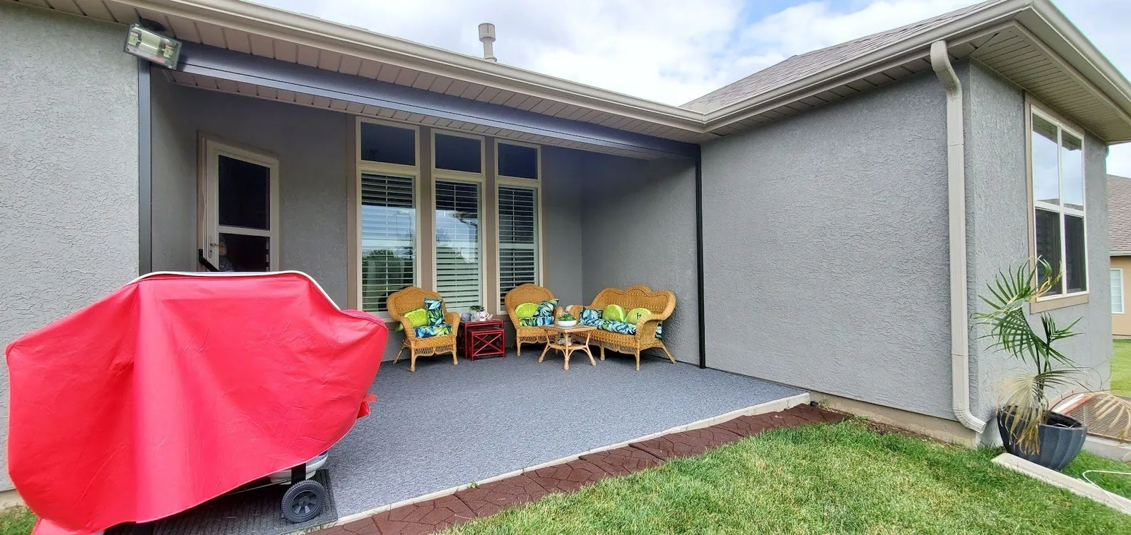 Ranch patio with the shade raised and the wicker chairs in view, installed by Solar Shield Blinds