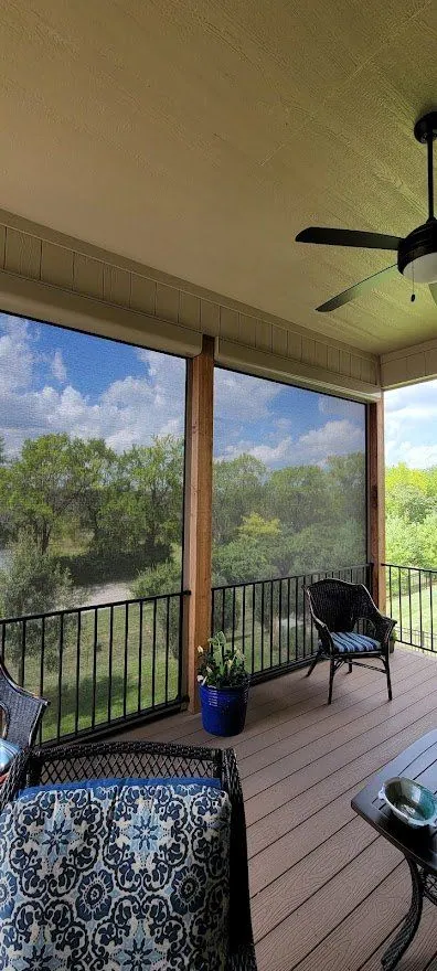 Corner of a screened deck with a ceiling fan and a patterned chair, installed by Solar Shield Blinds