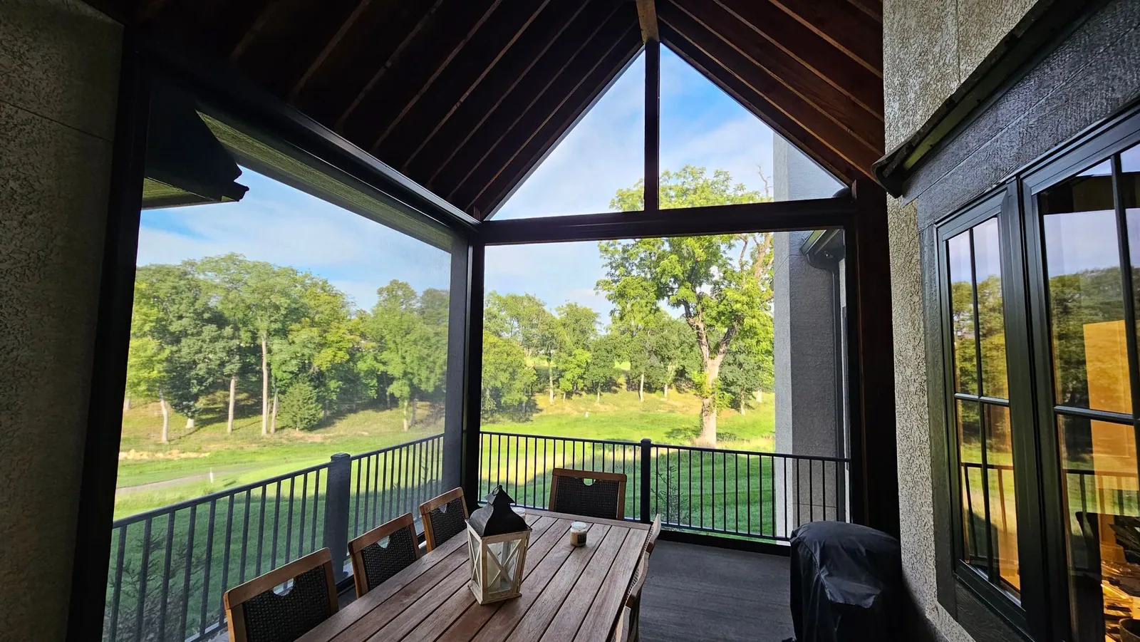 Screened porch with a table and chairs and a view of the golf course, installed by Solar Shield Blinds