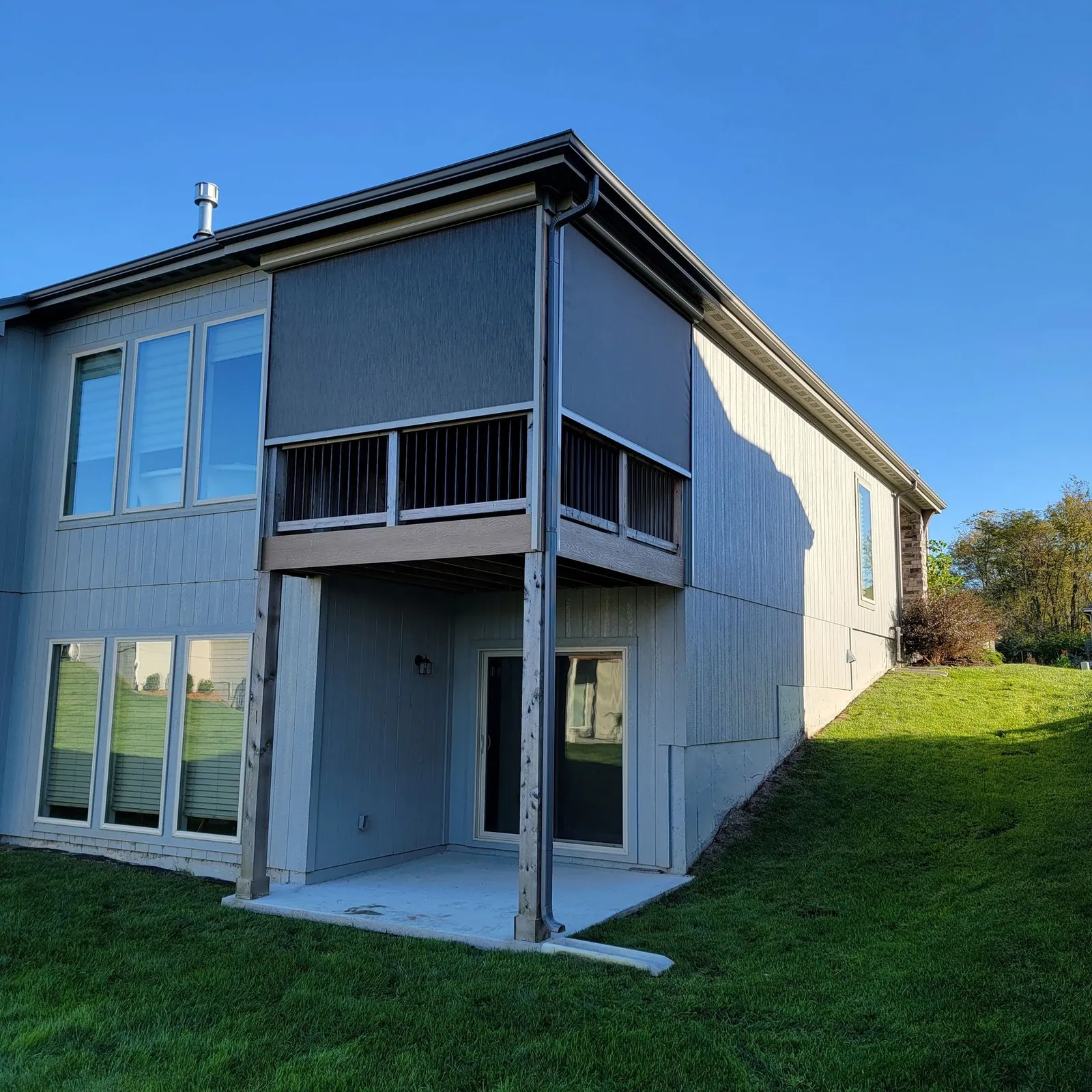 Upper deck shade lowered on a two story gray home, installed by Solar Shield Blinds