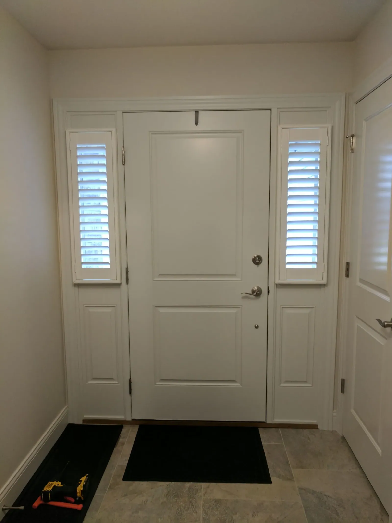 Plantation Shutters on both sidelights of a white entry, louvers open
