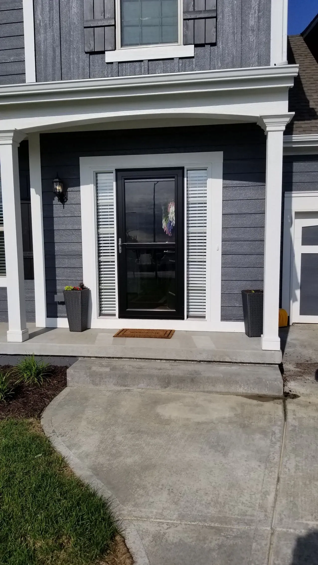 From the porch, a white shutter fills the sidelight beside a black door