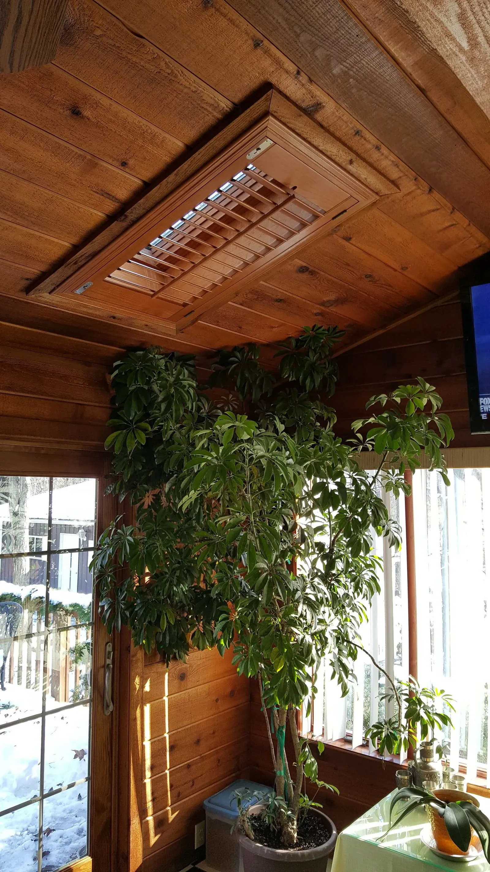 A stained wood shutter set into a cedar plank ceiling skylight