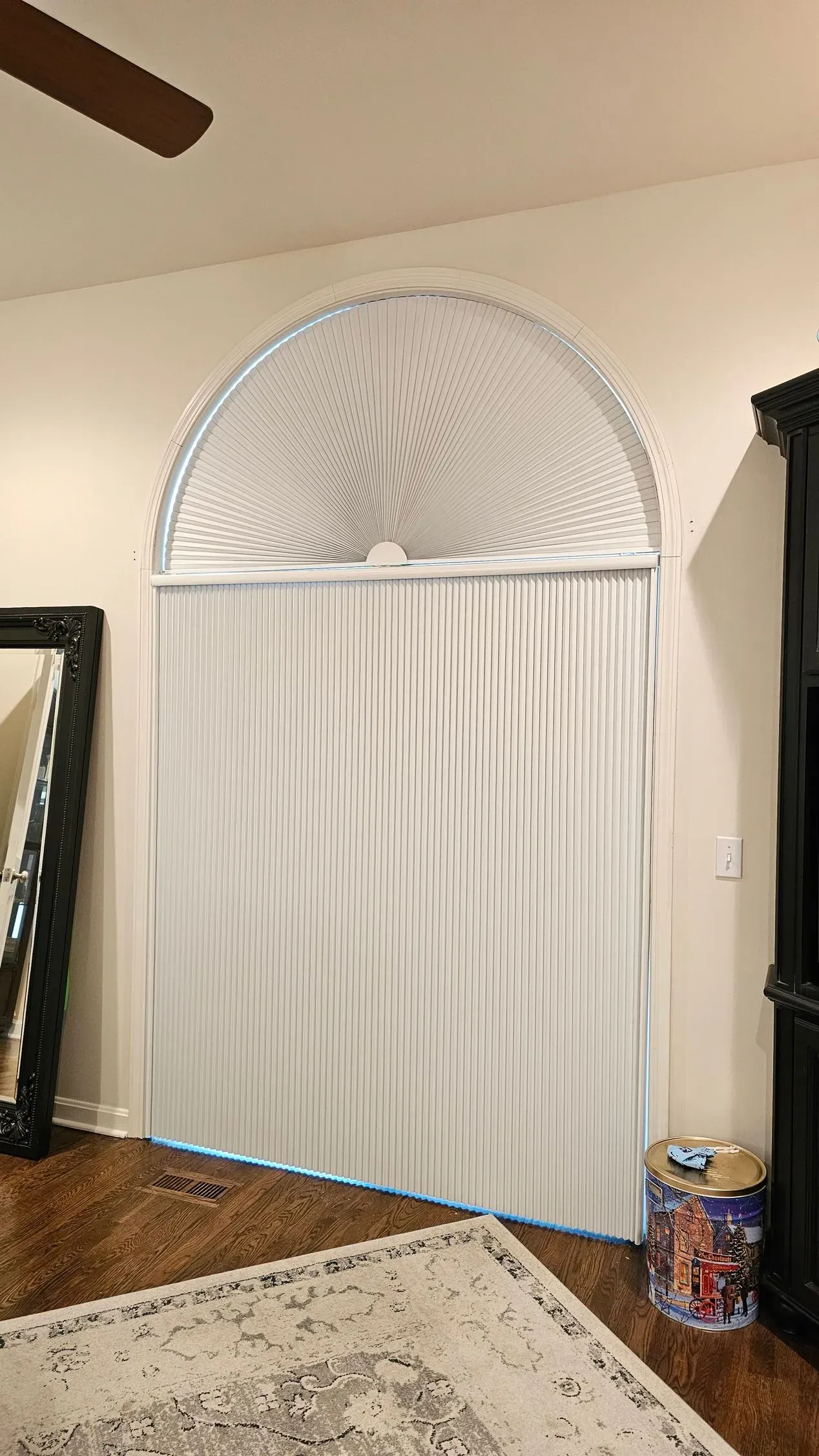 A pleated fan arch above a vertical honeycomb shade on an arch top window