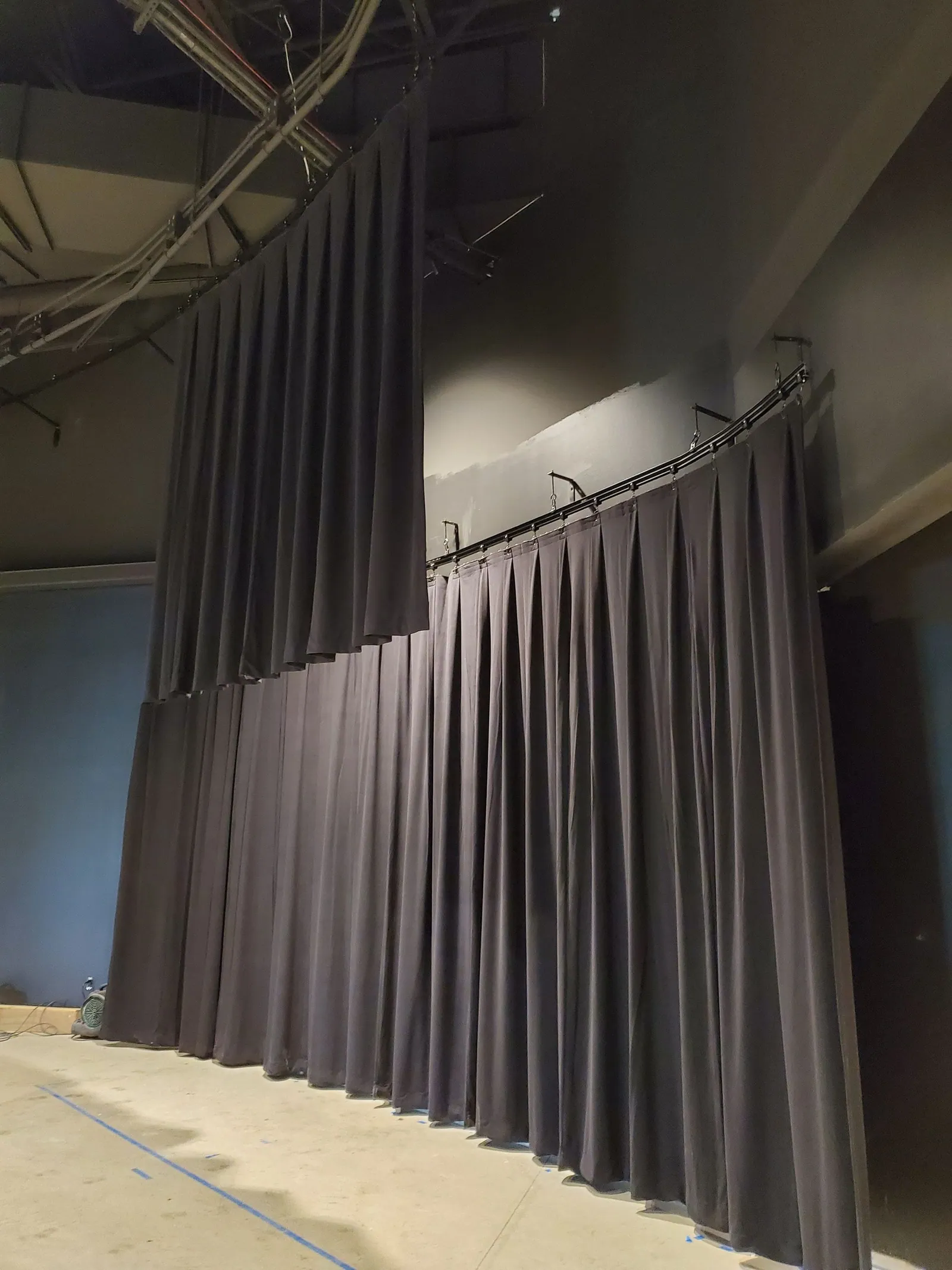 Black back curtains being hung from a curved track, with the carriers visible along the top
