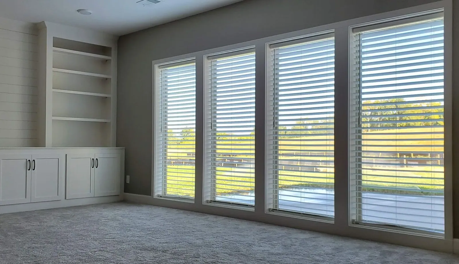 Faux wood blinds tilted open across tall windows