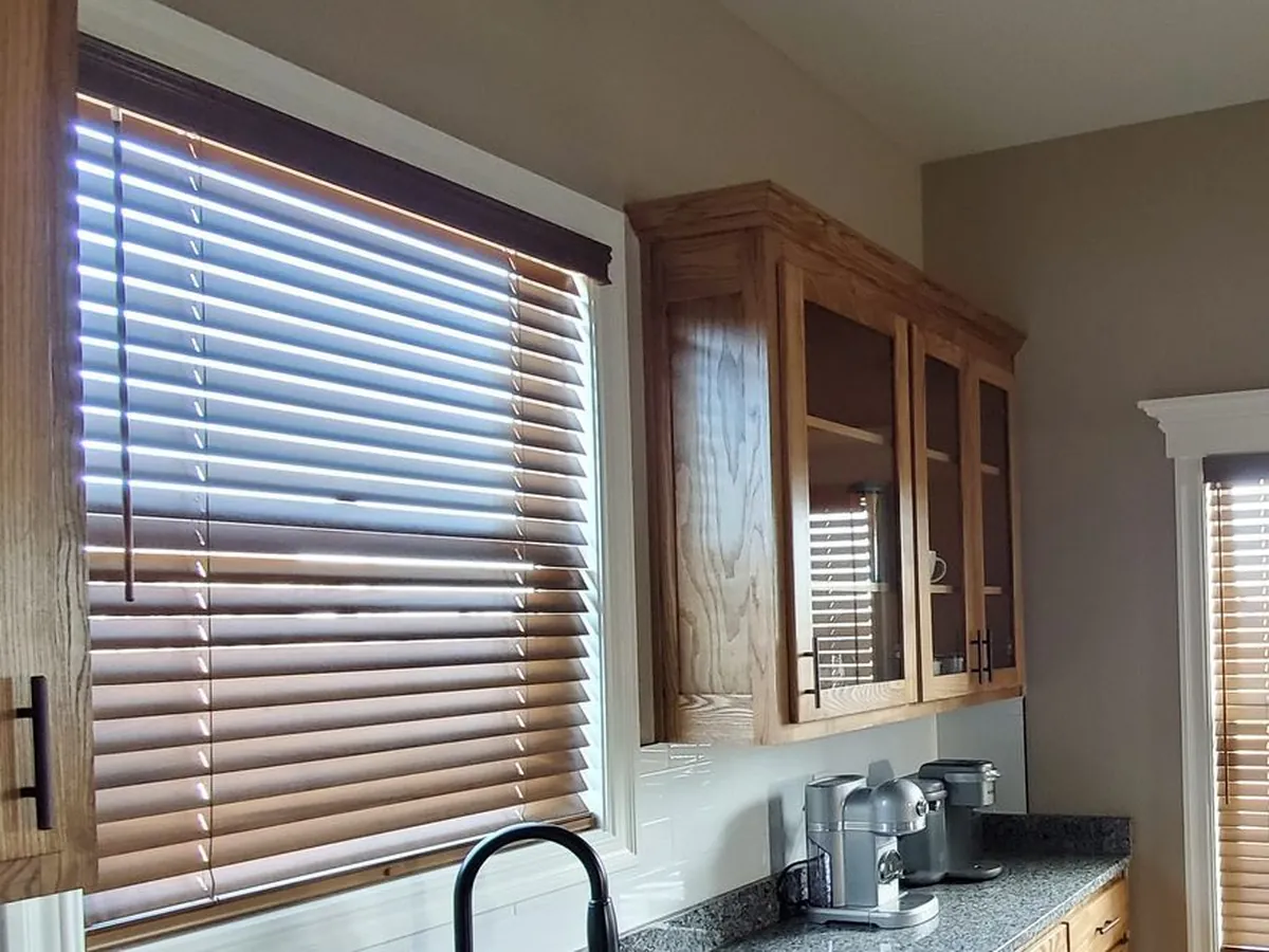 Stained real wood blinds on a kitchen window, installed by Solar Shield Blinds