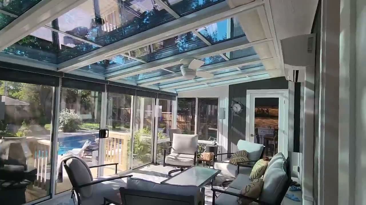 Automated Honeycomb Shades on the glass roof of a sunroom beside a pool